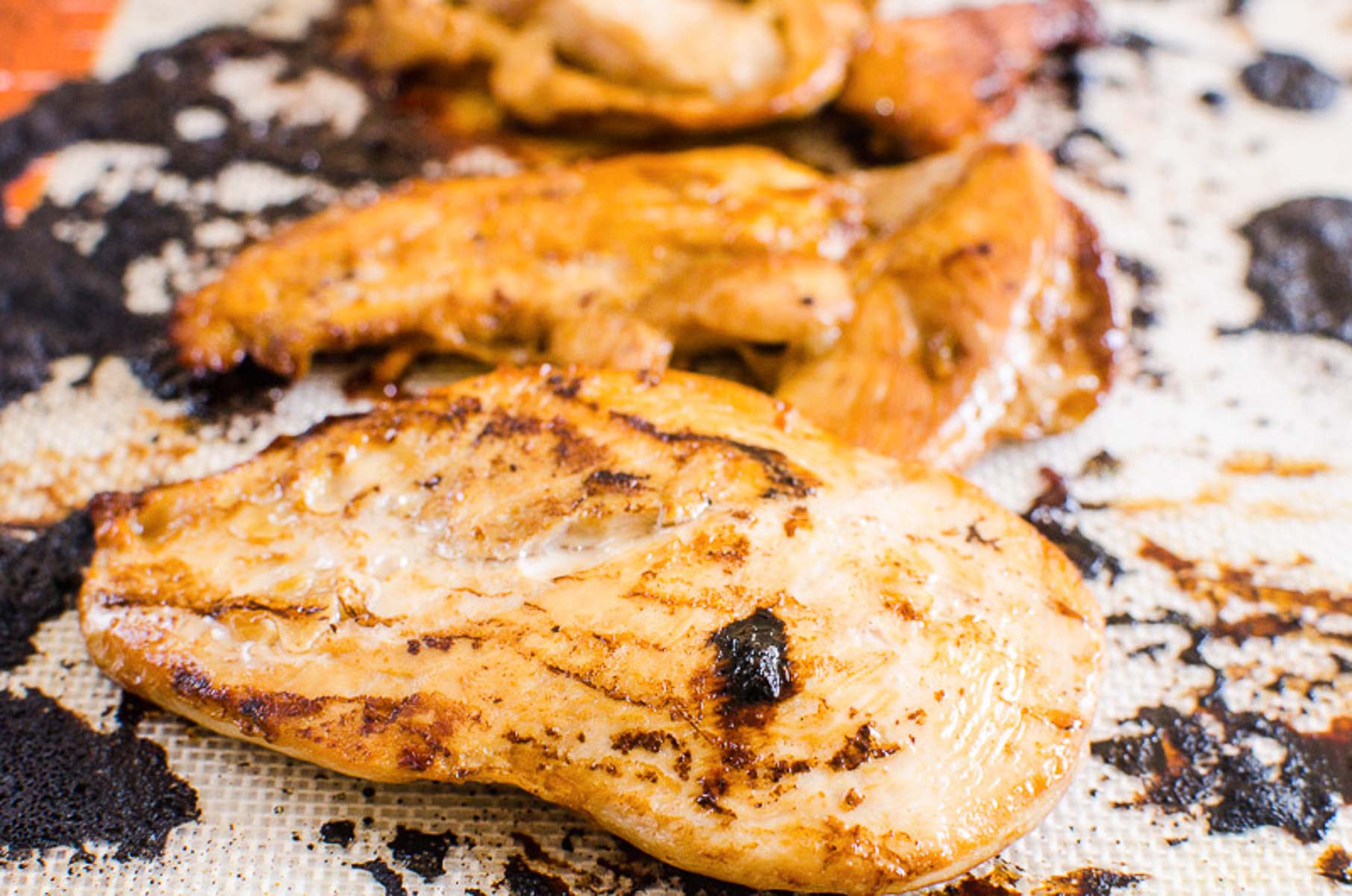 Chicken breast on silicone lined baking sheet.